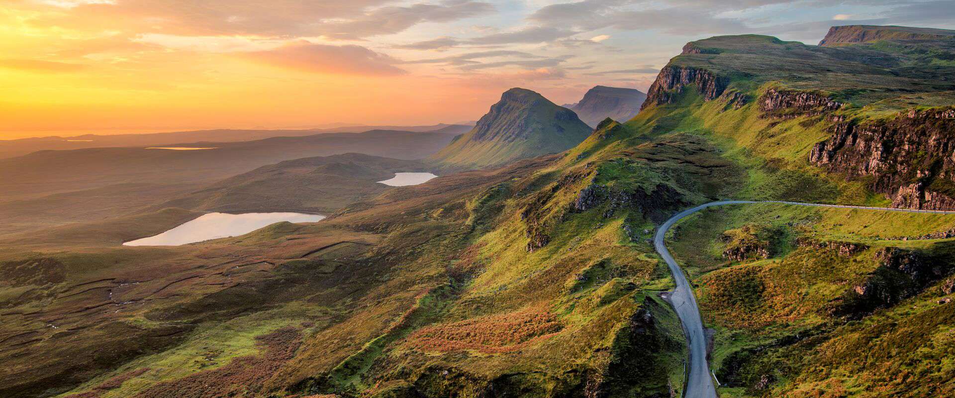 A serene loch surrounded by rolling green hills in the Scottish Highlands.